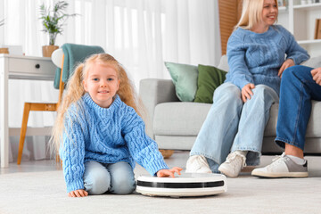 Poster - Little girl with robot vacuum cleaner and her parents at home