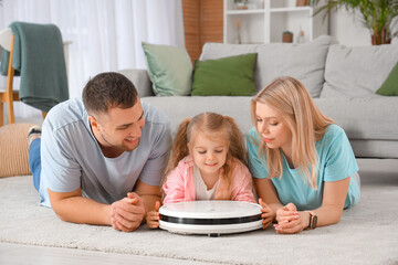 Poster - Happy family with robot vacuum cleaner lying on carpet at home