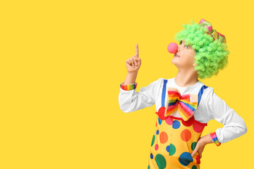 Poster - Funny little boy in clown costume with raised index finger on yellow background. April Fools Day celebration