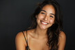© pham - A smiling Hispanic woman poses in a studio setting, wearing a black bra top