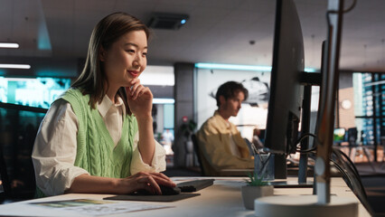 Fototapete - Asian Woman Using Desktop Computer And Designing In 3D Modelling Software Unique World And Characters For Survival Video Game In Diverse Office. Female Game Designer Creating Immersive Gameplay