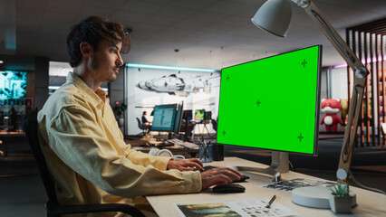 Aufkleber - Caucasian Man Using Desktop Computer with Mock-up Green Screen Chromakey. Male Concept Artist Working in Game Design Startup Diverse Office, Creating Immersive Gameplay For New Survival Video Game.