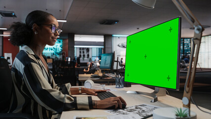 Poster - Portrait of Creative Black Female Sitting at a Desk Using Desktop Computer with Mock-up Green Screen. Female Concept Artist Working in Game Design Startup Office, Creating Immersive Gameplay.