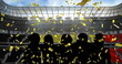Golden confetti falling over silhouette of fans cheering against sports stadium
