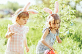 Fototapeta Dmuchawce - Easter egg hunt. Group Of Children Wearing Bunny Ears Running To Pick Up colorful Egg On Easter Egg Hunt In Garden. Easter tradition