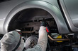 © Михаил Решетников - An auto mechanic applies anti-corrosion mastic to the underbody of a car.