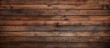 A closeup of a hardwood plank wall with a brown wood stain, showcasing the natural pattern of the building material. The blurred background highlights the beauty of the hardwood flooring
