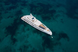 Fototapeta  - White large Mega yacht on azure water aerial view. A large expensive white yacht is anchored, top view. White yacht transparent turquoise water air view.