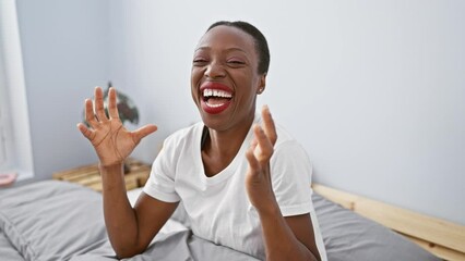 Wall Mural - Excited african american woman celebrating madly in bedroom, joyful success win lying on bed, arms raised