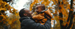 dark-skinned dad holds his little son in his arms and both laugh merrily against the backdrop of an autumn landscape close-up