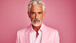 Handsome elderly elegant Latino with gray hair, on a pink background, banner, active old age.