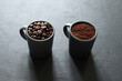 Due tazze di caffè grigie con chicchi di caffè e caffè macinato isolati su sfondo grigio. Vista dall'alto. Copia spazio.