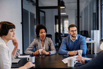 Wall Mural - An interracial team is listening to their leader at the boardroom on a meeting.