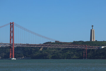 Wall Mural - 25 April Bridge and the statue of Jesus over Tagus River. Landmarks from Lisbon, Portugal, during a sunny day with blue sky.