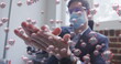 Image of covid 19 cells floating over man wearing face mask, sanitizing his hands in office