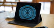 Image of blue circular scanner on black screen of tablet on table in cafe