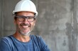 portrait of smiling man builder or engineer in blue T-shirt and white helmet in a renovated room