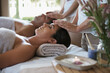 © Katie/peopleimages.com - Facial massage, hands and couple in spa to relax on bed for luxury pamper treatment together in hotel. Beauty, head or zen woman with man at resort or salon for natural healing benefits or skincare