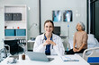 © Nuttapong punna - Young female doctor in white medical uniform using laptop and tablet talking video conference call at desk,Doctor sitting at desk and writing a prescription for her patient
