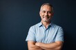 © PNG&Background Image - Middle-aged man wearing a blue office shirt confidently standing with arms crossed on a dark blue background with copy space.