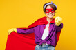 Young woman wears purple shirt rubber gloves super hero suit casual clothes do housework tidy up point finger camera on you isolated on plain yellow background studio portrait. Housekeeping concept.