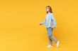 © ViDi Studio - Full body side view young IT woman she wear blue shirt white t-shirt casual clothes hold use work on laptop pc computer walk go isolated on plain yellow background studio portrait. Lifestyle concept.