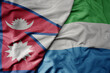 big waving national colorful flag of sierra leone and national flag of nepal .