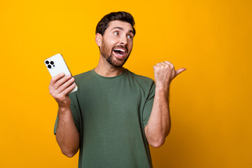 Canvas Print - Photo portrait of attractive young man hold gadget point look empty space wear trendy khaki clothes isolated on yellow color background