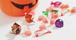 Happy halloween text banner with bat icon against pumpkin shaped bucket full of halloween candies