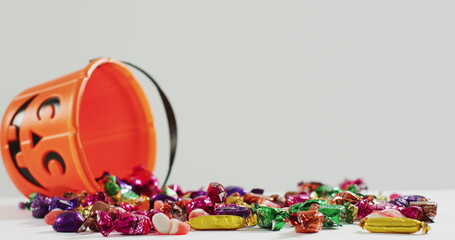 Canvas Print - Happy halloween text banner against halloween candies fallen from pumpkin shaped bucket