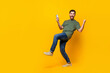 © deagreez - Full size photo of attractive young man hold gadget winning raise fists wear trendy khaki clothes isolated on yellow color background
