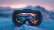 A close-up of a pair of ski goggles with a reflection of a mountain landscape. The goggles are sitting on the snow.