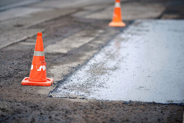 traffic cones separated repaired section of asphalt road from cars. repairing asphalt pavement on th
