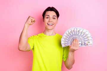 Poster - Photo portrait of handsome teen male hold money fan raise fist wear trendy yellow garment isolated on pink color background