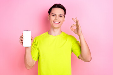 Poster - Photo portrait of handsome teen male hold device white screen show okey dressed stylish yellow garment isolated on pink color background