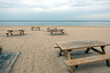 Several wooden tables and benches on empty sandy beach in Jurmala resort seacoast in low season