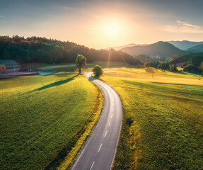 Wall Mural - aerial view of road in green meadows at sunset in summer. top drone view of rural road, mountains, f