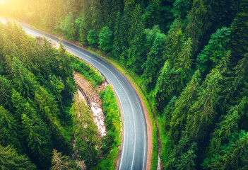 Wall Mural - aerial view of road in beautiful green forest at sunset in summer. colorful landscape with roadway, 