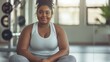 Black woman, fat body positive beauty, wearing a white T-shirt and gray yoga pants, sitting in the gym, full figure. Generative ai