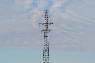 high power line tower on a background of blue sky with clouds