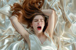 Young European red-haired woman having orgasm. Beautiful woman with open mouth and closed eyes enjoying sex lying in bed among silk. Sexual experience, masturbation, cunnilingus.