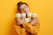 Tired sleepy young woman with coffee. Sleepy exhausted student girl holding a lot of takeaway coffee cups on studio background with copy space. Need more coffee, falling asleep, I hate Mondays concept