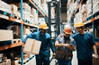 © Davor - Happy warehouse workers looking at phone, men with hard hats in storage facility