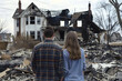 Backview of couple looking at their burnt out house, aftermath of fire disaster