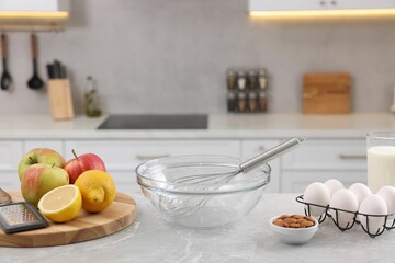 Wall Mural - Metal whisk, bowl, grater and different products on gray marble table in kitchen