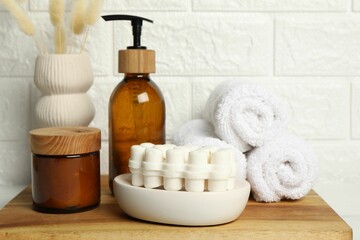 Different bath accessories, personal care products and spikelets in vase on table near white brick wall, closeup