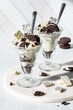 Two delicious chocolate cookie ice cream parfaits with ingredients all around.