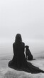© IULIIA SAVINA - Lonely woman dressed in black sitting with dog in the field and looking to fog.