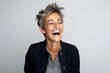© Igor - Portrait of a happy mature woman laughing against a grey background.