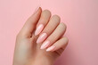 © jannik27s - female hand with pink french nails on a pink background